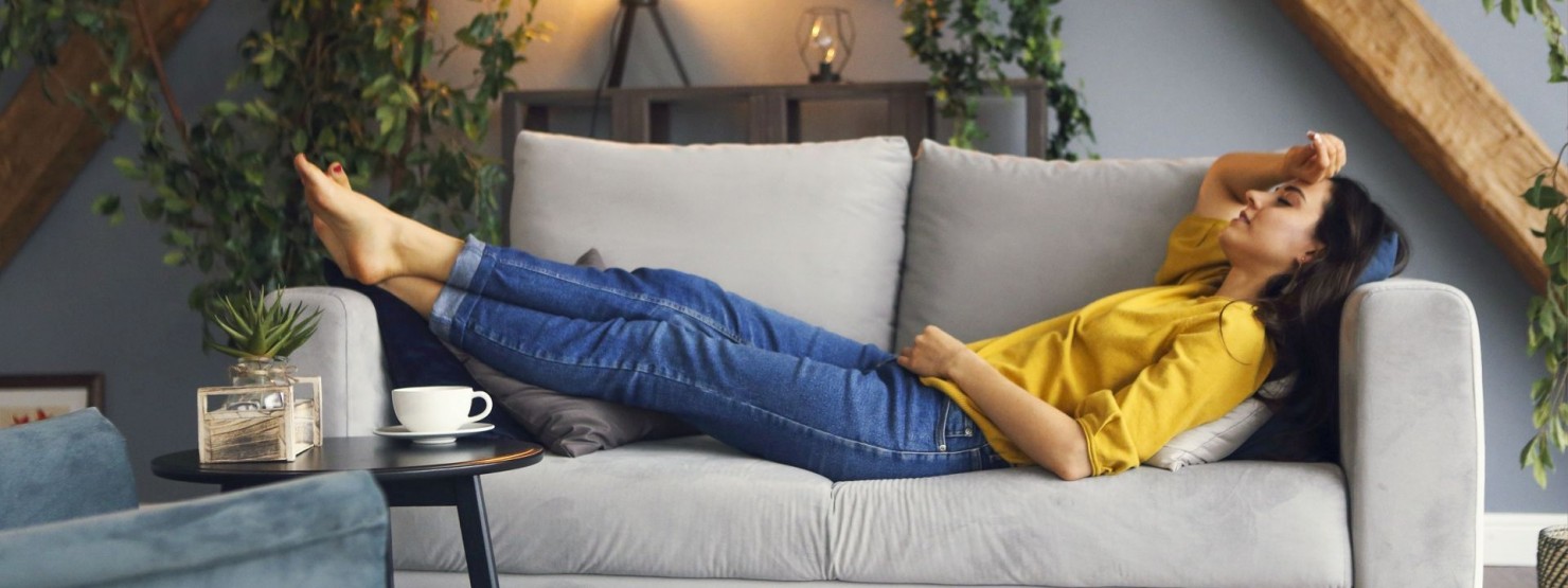 Eine etwa 30-jährige Frau liegt auf dem Sofa für einen Powernap