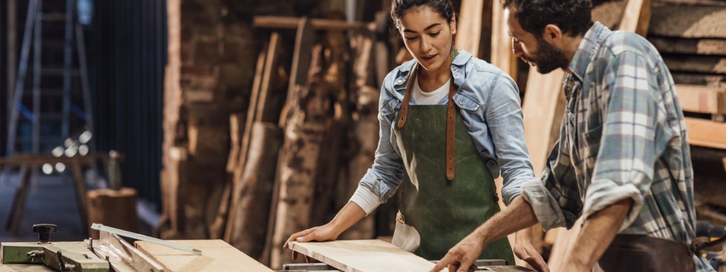 Ein Lehrling wird vom Handwerksmeister in einer Werkstatt angeleitet.