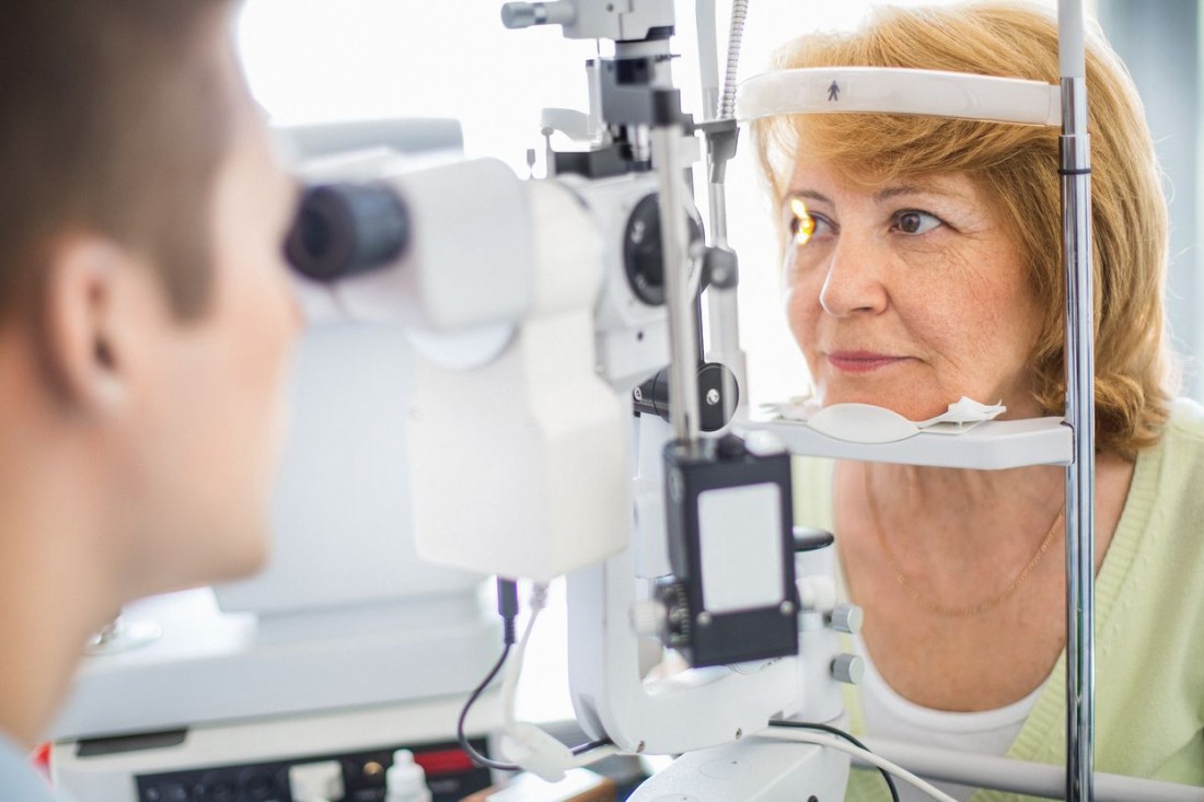 Eine etwa 60 jährige Frau wird mit eine Spaltlampe am Auge untersucht. 