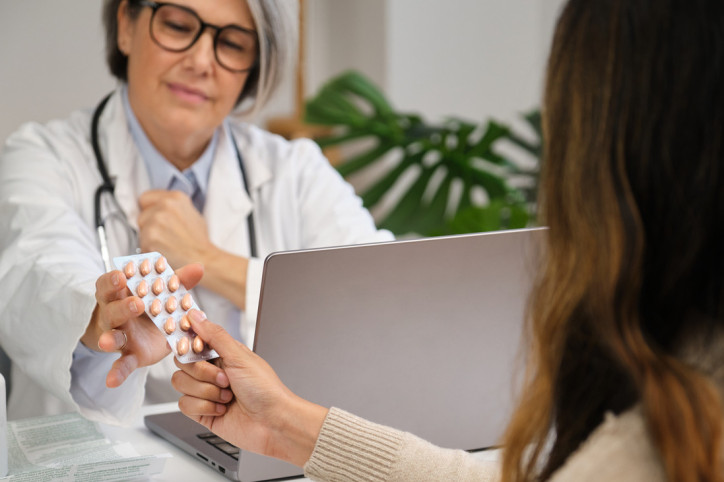 Eine Patientin bekommt von einer Ärztin Medikamente ausgehändigt.