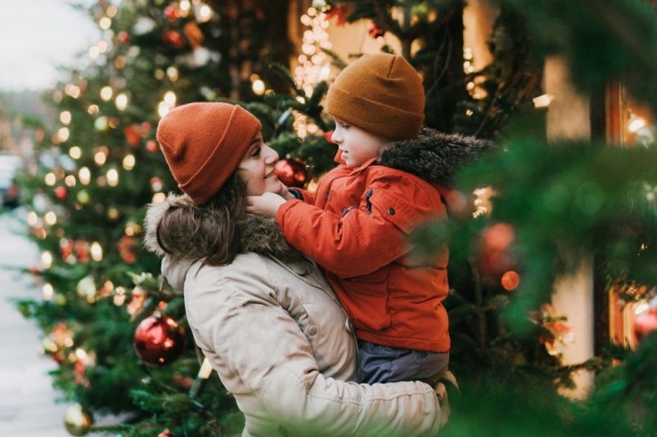 Eine Mutter trägt ihren Sohn auf dem Weihnachtsmarkt.