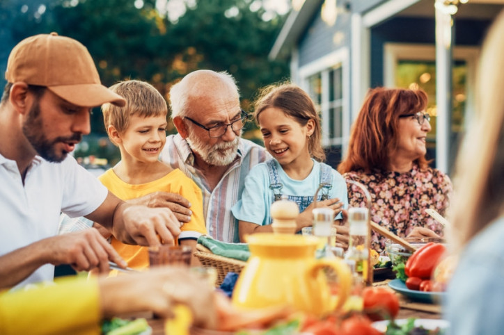 Eine Familie isst gemeinsam fröhlich am Tisch und ernährt sich mediterran.