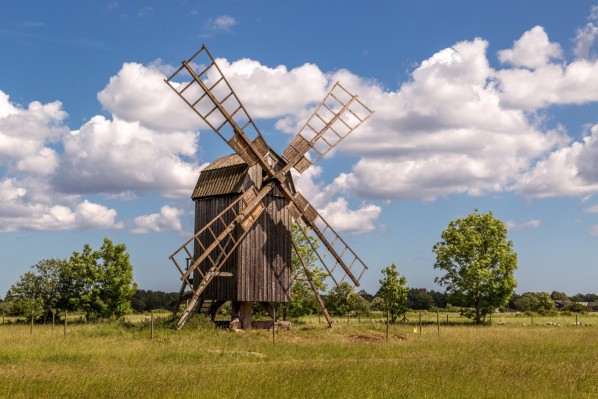 Eine historische Windmühle aus Holz steht auf einem Feld