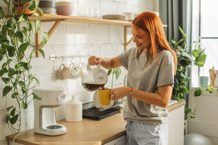 Eine Frau gießt sich eine Tasse Filterkaffee ein