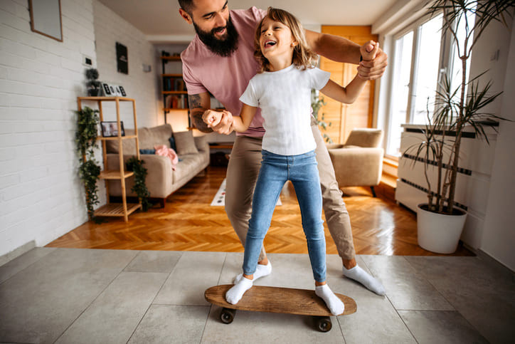 Ein Vater bringt seiner Tochter Zuhause das Skaten bei