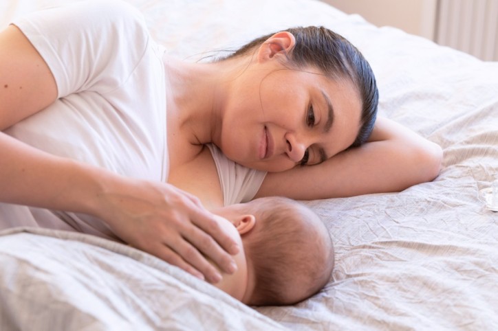 Eine Mutter stillt ihr Kind im Liegen.
