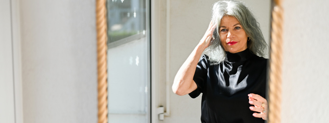 Eine Frau mit Brustprothese schaut sich im Spiegel an.