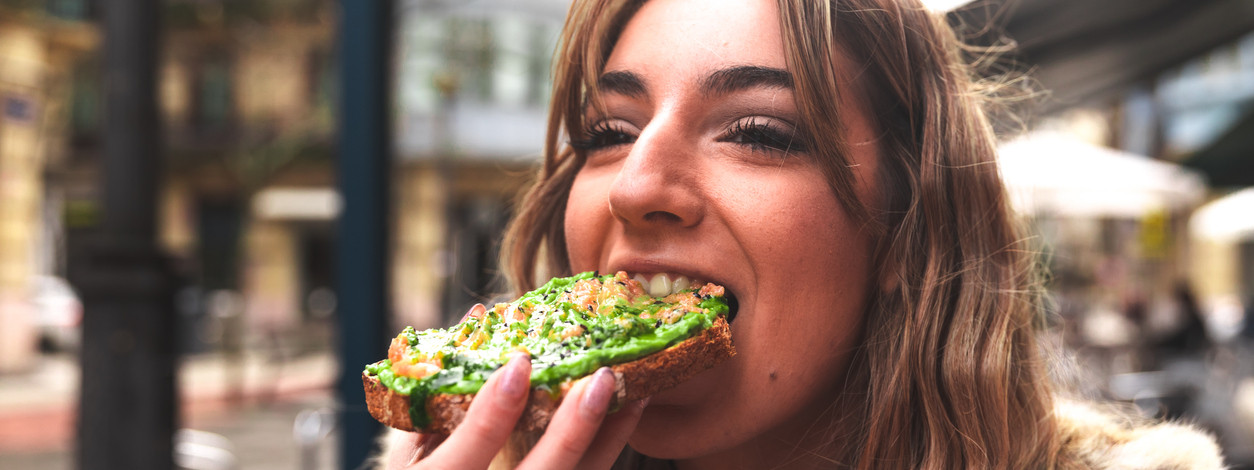 Frau mitte 20 beißt in ein Avocadobrot