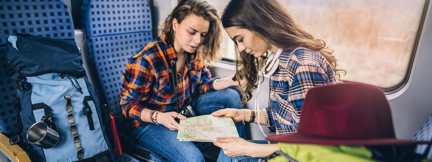 Zwei junge Frauen reisen mit viel Gepäck im Zug.