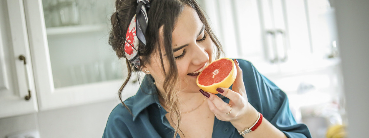 Eine Frau beißt in eine Grapefruit, die viele Bitterstoffe enthält