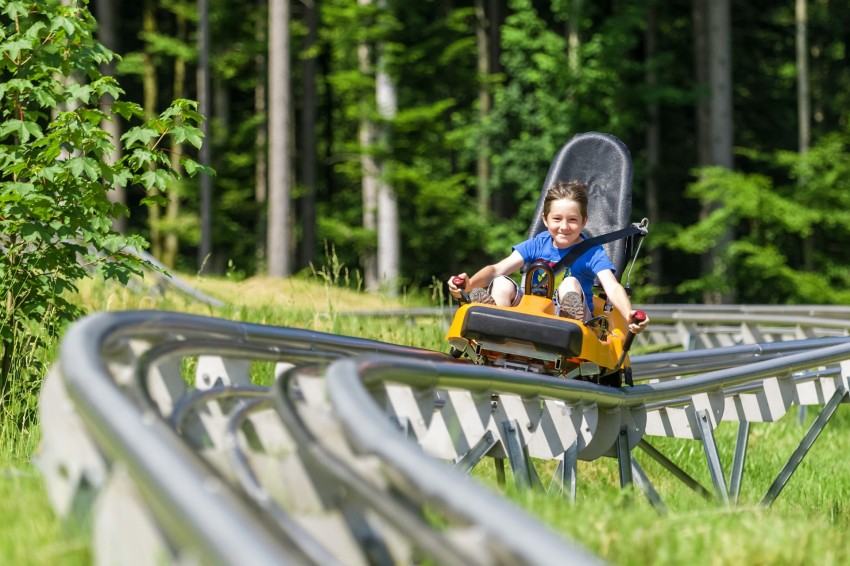 Junge fährt auf einer Sommerrodelbahn. 