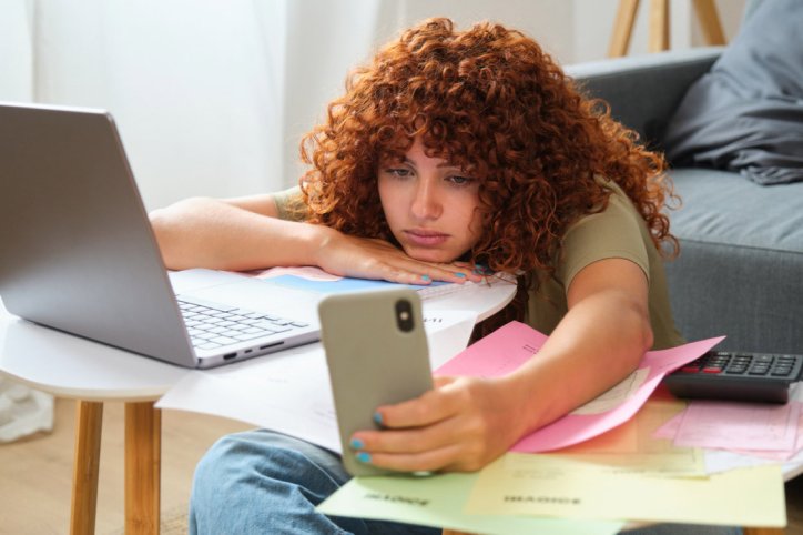 Eine Frau prüft gelangweilt ihr Smartphone.