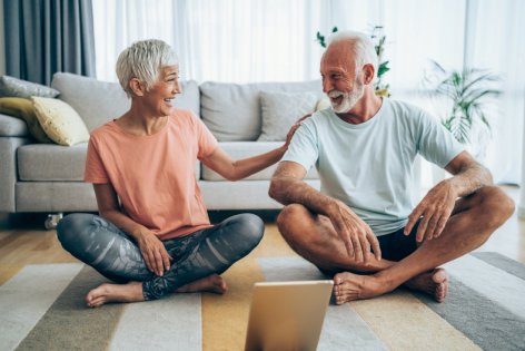Ein älteres Paar macht zu Hause gemeinsam Yoga.