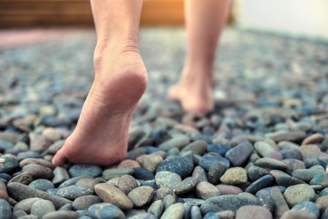 Nackte Füße laufen über einen Steinweg.