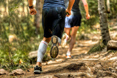 Zwei Personen laufen beim Trailrunning durch den Wald