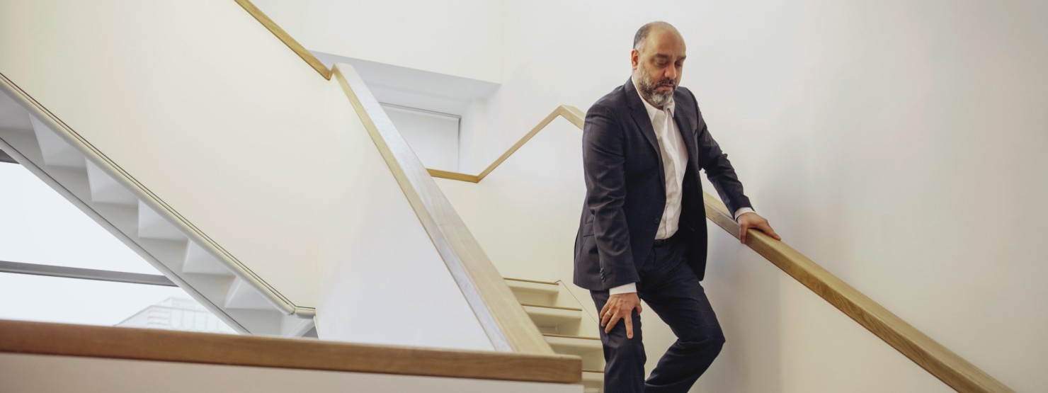 Ein Mann mit Schmerzen im Knie versucht eine Treppe herab zu gehen