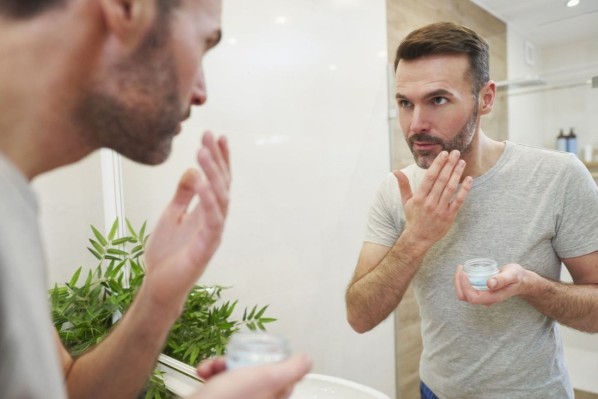 Ein Mann cremt sich mit einer antioxidativen Creme das Gesicht ein.