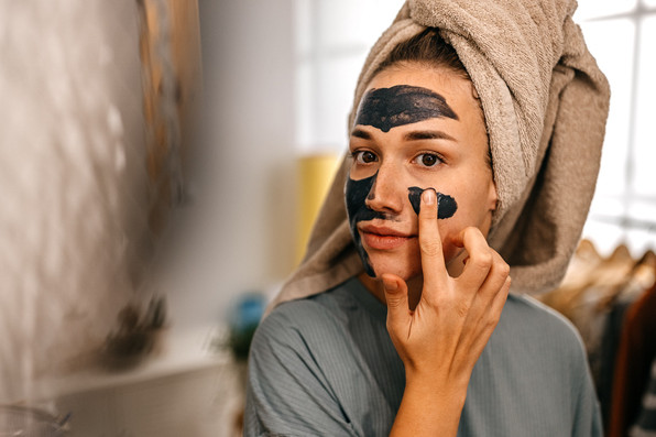 Eine Frau trägt eine Gesichtsmaske mit Heilerde auf.