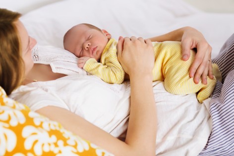 Frau mit ihrem Baby gemütlich im Bett.