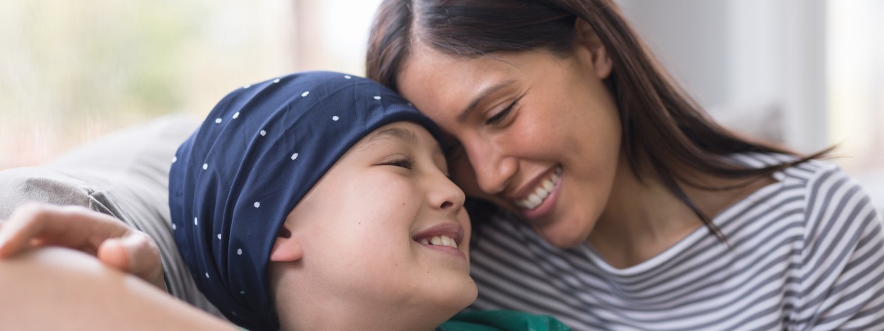 Ein an Krebs erkranktes Kind wird von seiner Mutter umarmt.