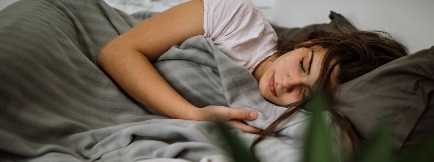 Eine junge Frau liegt im Bett und schläft.