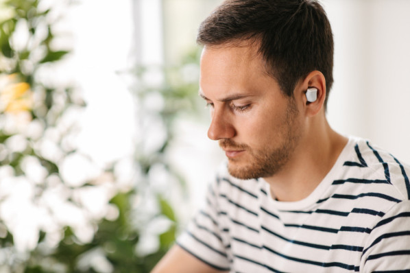 Mann arbeitet mit in-Ear-Kopfhöerern am laptop