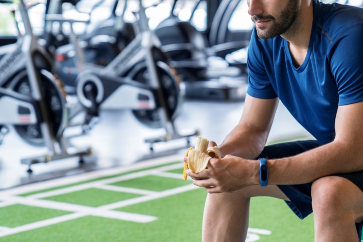 Ein Mann, der Carboloading nutzt, isst eine Banane in einer Trainingspause