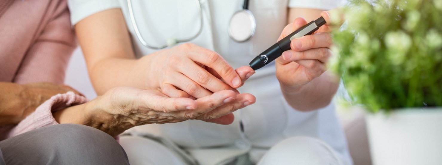 Eine Ärztin misst bei einer Seniorin den Blutzucker mit Hilfe eine Blutzuckermessgerätes am Finger.