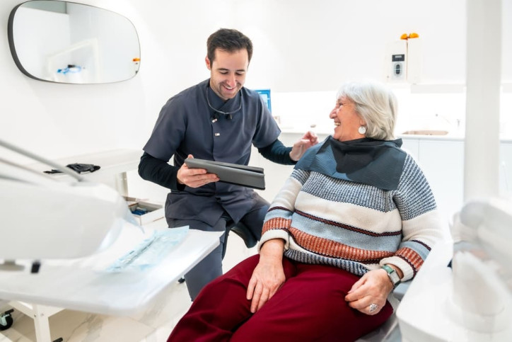 Junger Zahnarzt behandelt Seniorin in seniorenfreundlicher Praxis