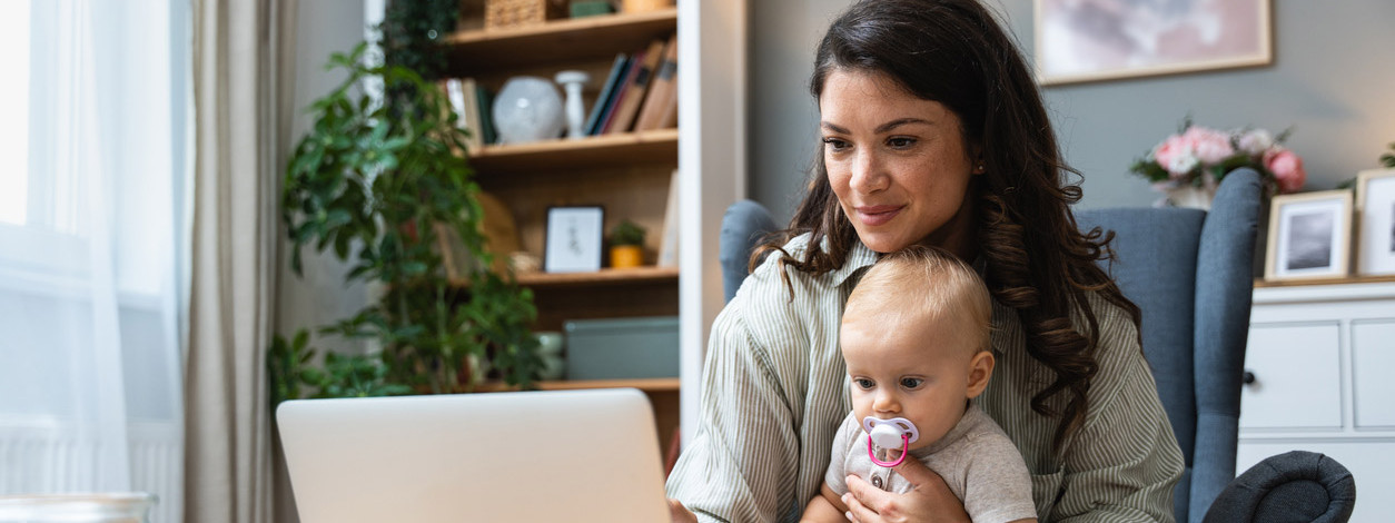 Eine frischgebackene Mutter informiert sich mit ihrem Baby über den Mutterschutz