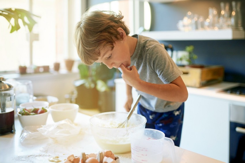 Junge nascht beim Backen aus der Schüssel