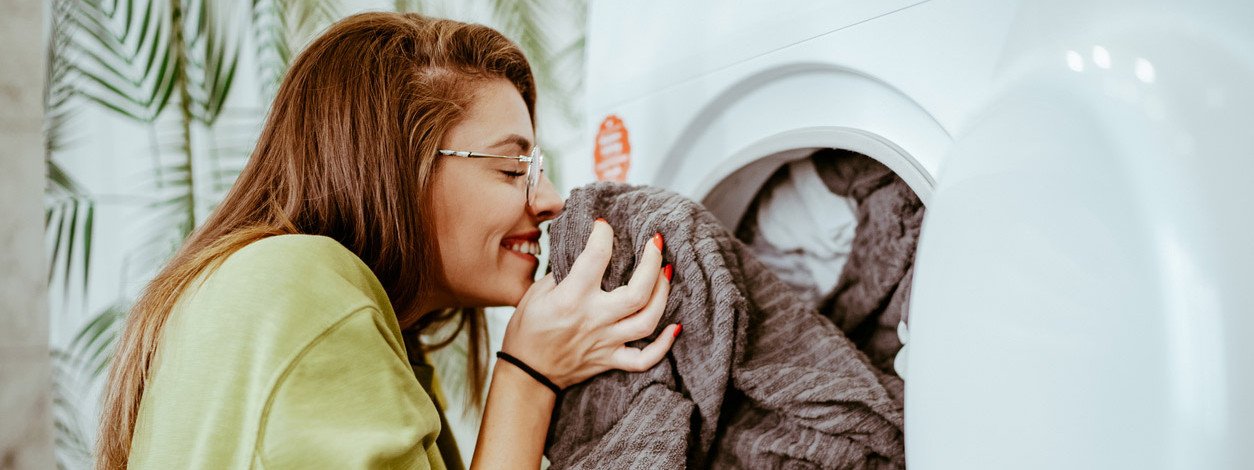 Eine junge Frau riecht an frisch gewaschener Wäsche