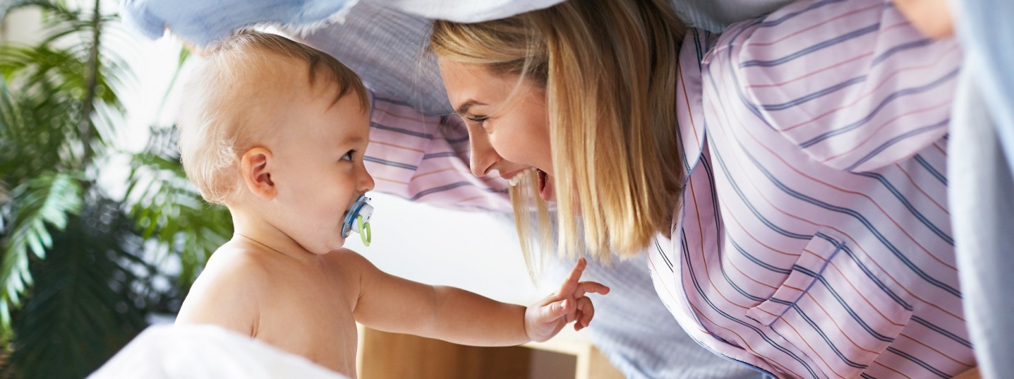 Mutter mit Baby spielend im Bett