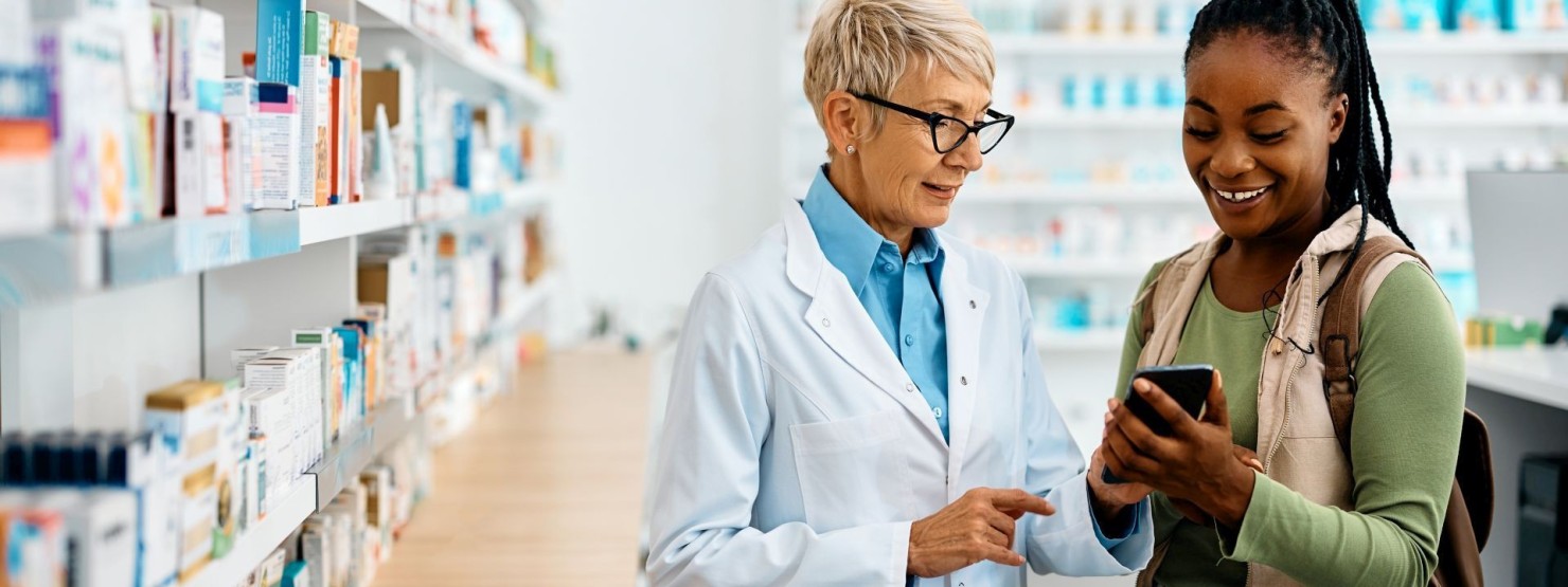 Eine etwa 25-jährige Frau lässt sich in der Apotheke von einer Apothekerin beraten.