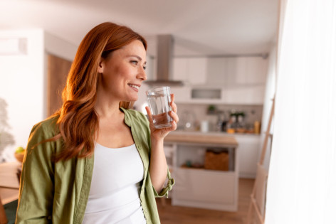 Eine Gruppe von Freunden sitzt im Außenbereich eines Restaurants und lacht ausgiebig. Dabei essen und trinken sie.