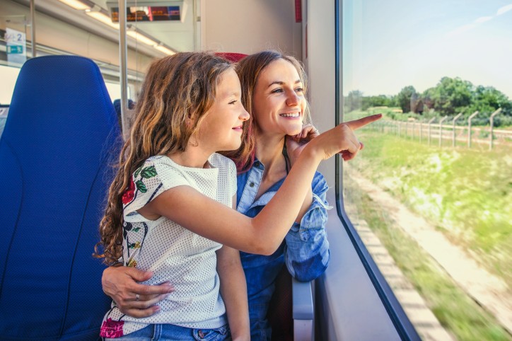 Frau schaut mit Kind auf dem Schoß aus dem Zugfenster