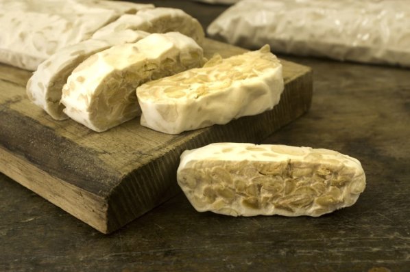 Tempeh liegt als Fleischersatz auf einem Brett