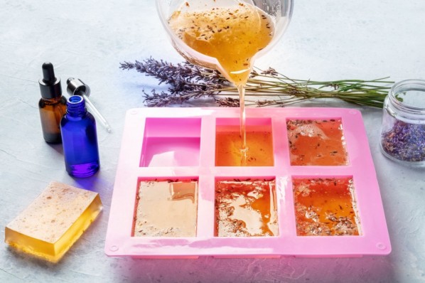 Organic handmade soap making. Diy cosmetic, the process of making. Liquid glycerin with essential oils and lavender buds is poured into a silicone soap mold