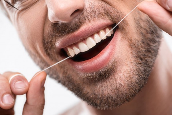 Ein Mann reinigt seine Zähne mit Zahnseide.