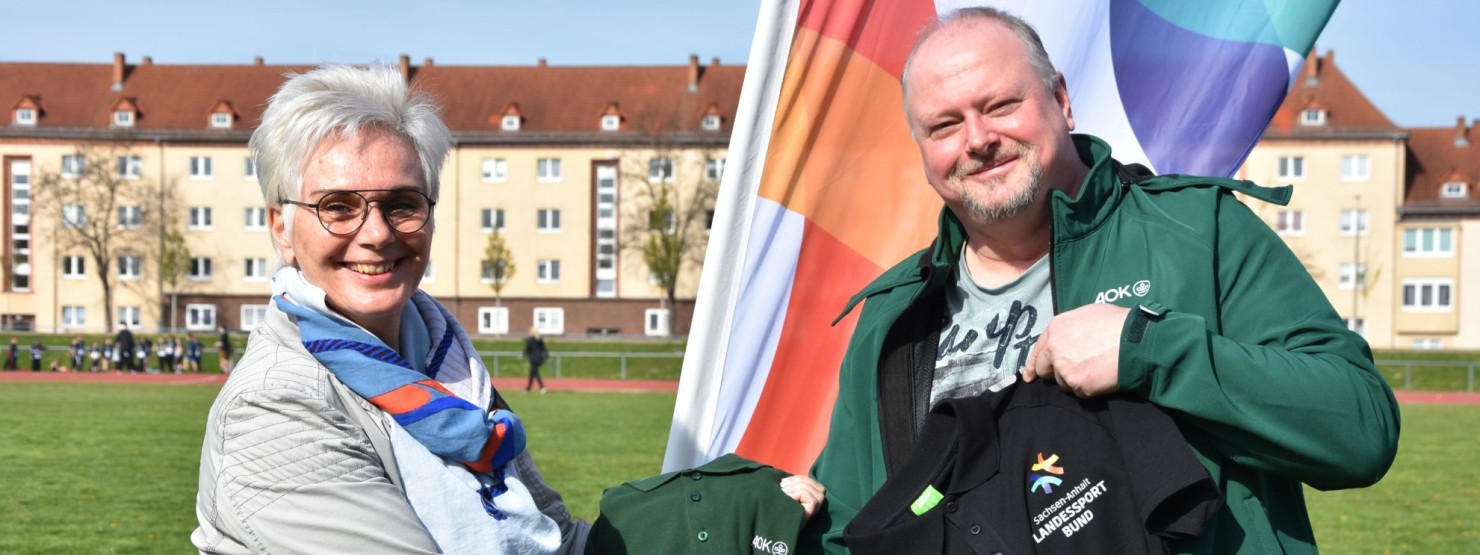 Silke Renk-Lange, Präsidentin des Landessportbundes, und Henry Saage, Landesrepräsentant der AOK Sachsen-Anhalt, beim symbolischen Trikottausch. Die Entscheidung über die weitere Kooperation haben beide Institutionen am Wochenende im Rahmen der 8. Sachsen-Anhalt-Spiele bekanntgegeben.