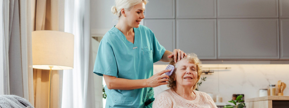 Pflegerin kämmt pflegebedürftiger Frau die Haare