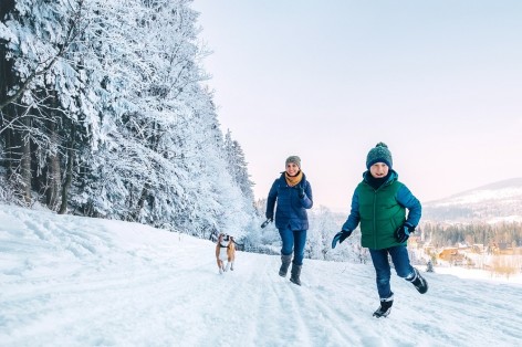 Mutter und sohn laufen durch verschneite Landschaft
