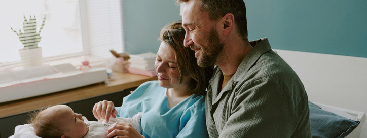 Junge Eltern halten Neugeborenes im Arm