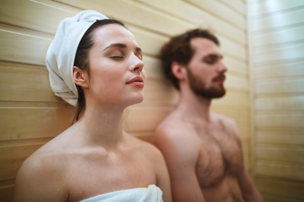 Mann und Frau mit geschlossenen Augen in der Sauna.