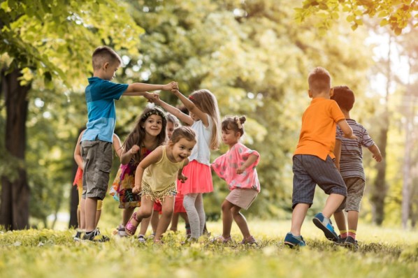 Gruppe von Kindern im Kindergartenalter toben auf einer Wiese im Freien