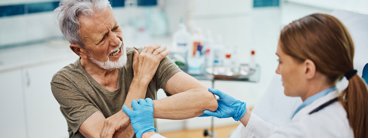 Eine neue Fachärztin für Orthopädie behandelt den Arm eines älteren Mannes