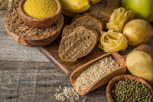 Kartoffeln, Brot und verschiedene Sorten Nudeln liegen auf einem Holzbrett.