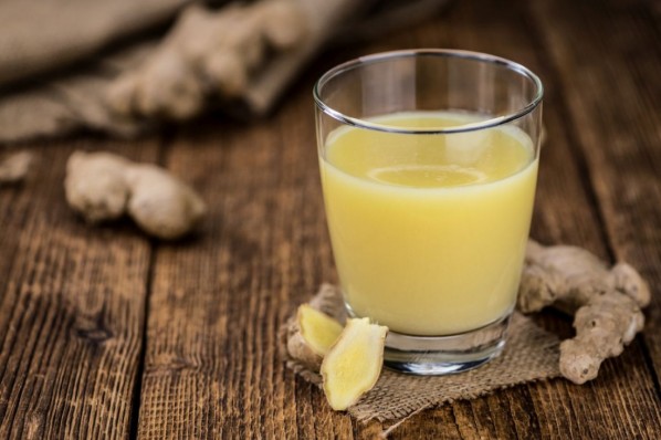 Healthy Ginger Sap on a wooden table as detailed close-up shot (selective focus)