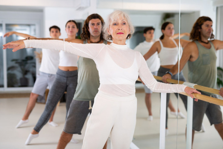 Eine Gruppe aus Frauen und Männern macht gemeinsam ein Barre-Workout