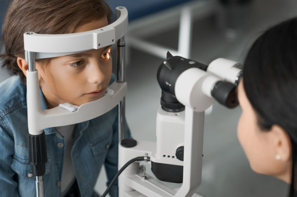 Ein Junge wird von einer Ärztin an Augen untersucht.
